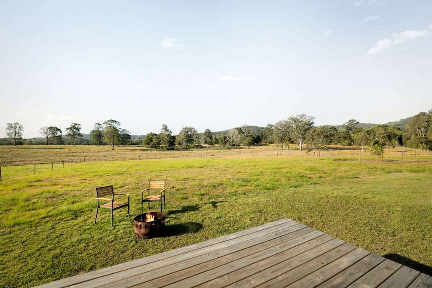 Un área de estar al aire libre con una terraza de madera, dos sillas y un brasero.