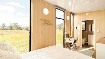 Ein Schlafzimmer mit einem großen Bett, einem Essbereich mit Tisch und Stühlen sowie einem Badezimmer mit Toilette und Waschbecken.