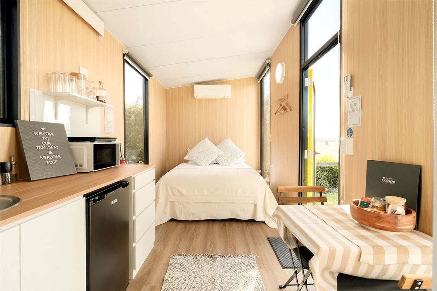 A compact room with a bed, a small kitchenette, and a window providing a view.