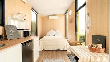 A compact room with a bed, a small kitchenette, and a window providing a view.