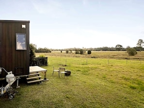 A small wooden structure with a window, a table, and chairs outside.