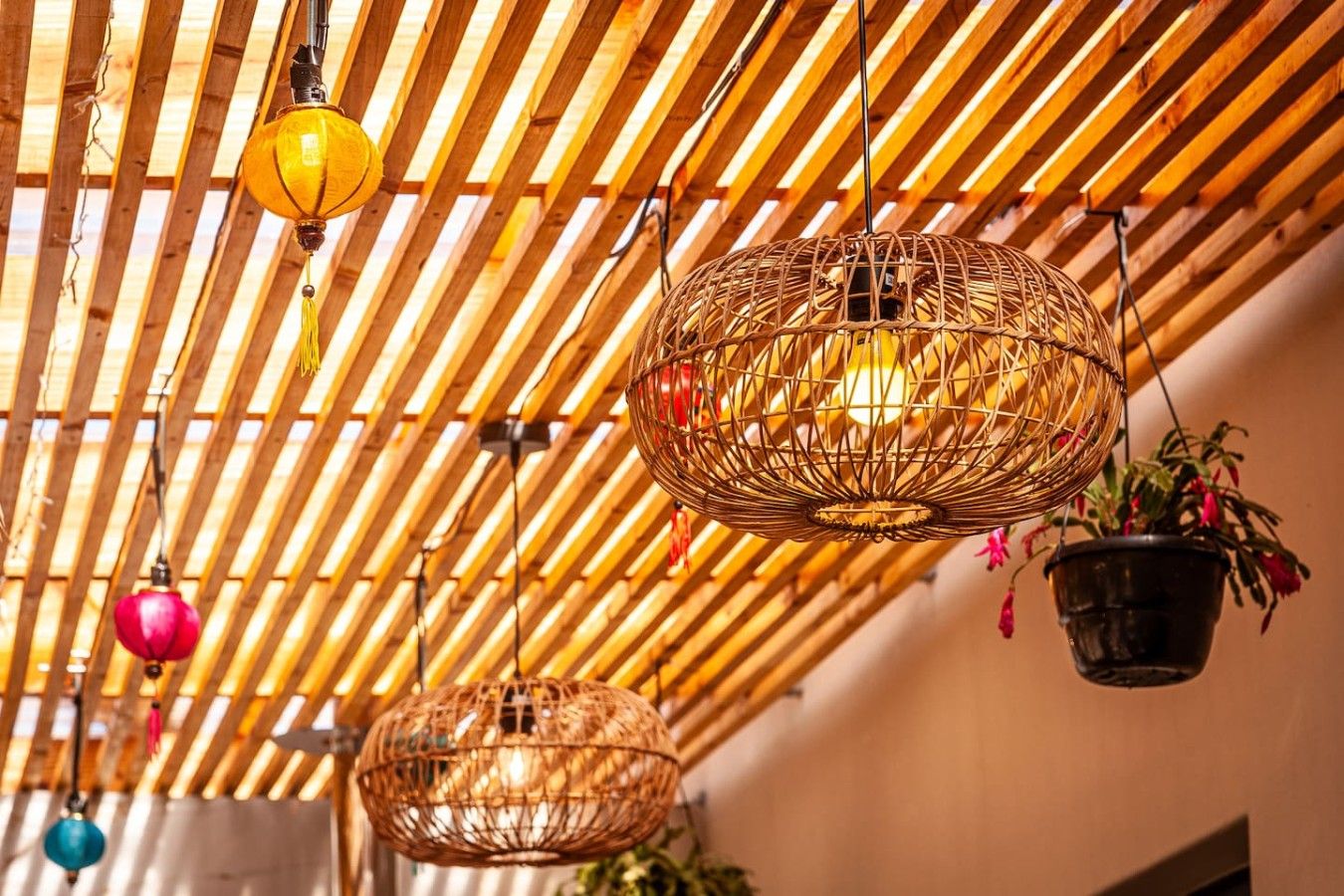 Un plafond avec des lambris en bois et des lampes en osier suspendues.