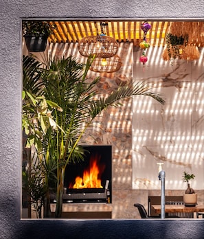 A fireplace with a fire, surrounded by potted plants and hanging decorations.