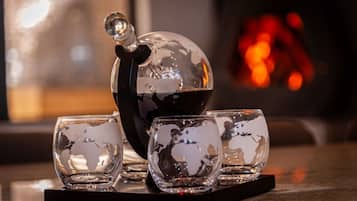 Kristallen glazen en een theepot op een onderzetter, met een onscherpe achtergrond die een knus interieur doet vermoeden.
