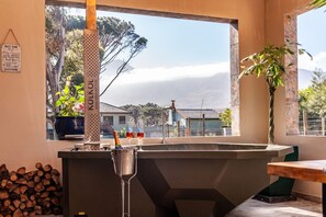 A bar area with a view of the mountains, a sign for a wood-fired hot tub, and a potted plant.