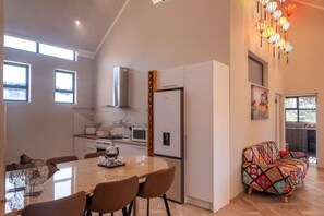 Eine moderne Küche mit Essbereich, einem Kühlschrank und einem farbenfrohen Sofa.