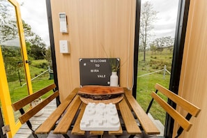 A wooden bench with a welcome sign, a small table, and a wall-mounted device.