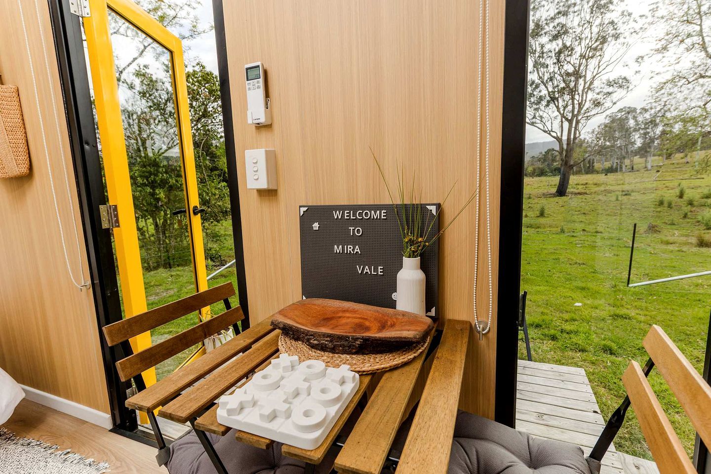 Un interior de madera con un banco, un letrero de bienvenida y vistas al exterior.