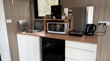 A compact kitchenette with a microwave, coffee maker, and a sink.