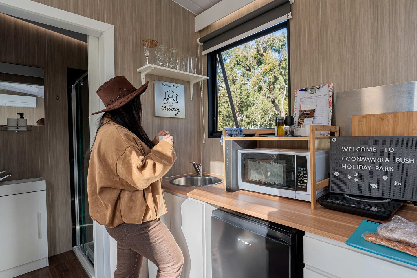 Una cucina moderna con forno a microonde, lavello e un cartello di benvenuto al Coonawarra Bush Holiday Park.