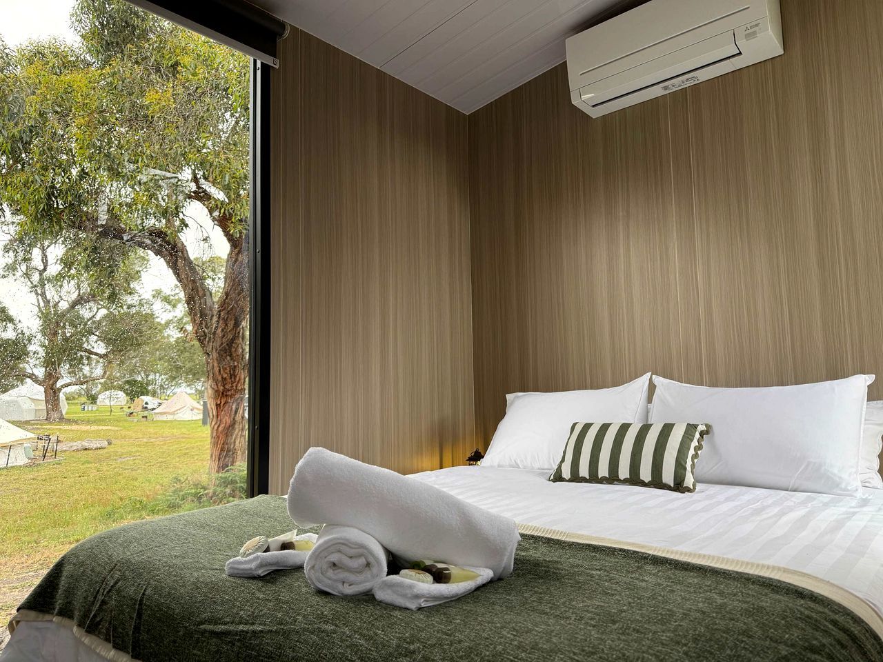 A hotel room with a bed, a window, and a view of the outdoors.