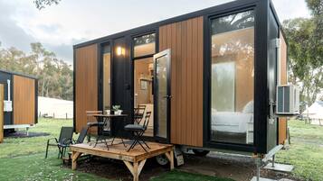 A compact, modern mobile home with a dining area and a sleeping space.