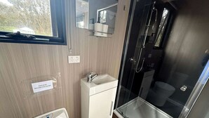 Casa de banho compacta com sanita, lavatório e chuveiro.