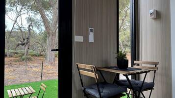 A room with a view of a garden, a table with chairs, and a potted plant.