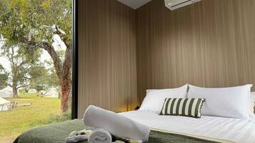 A hotel room with a bed, a window, and a view of the outdoors.