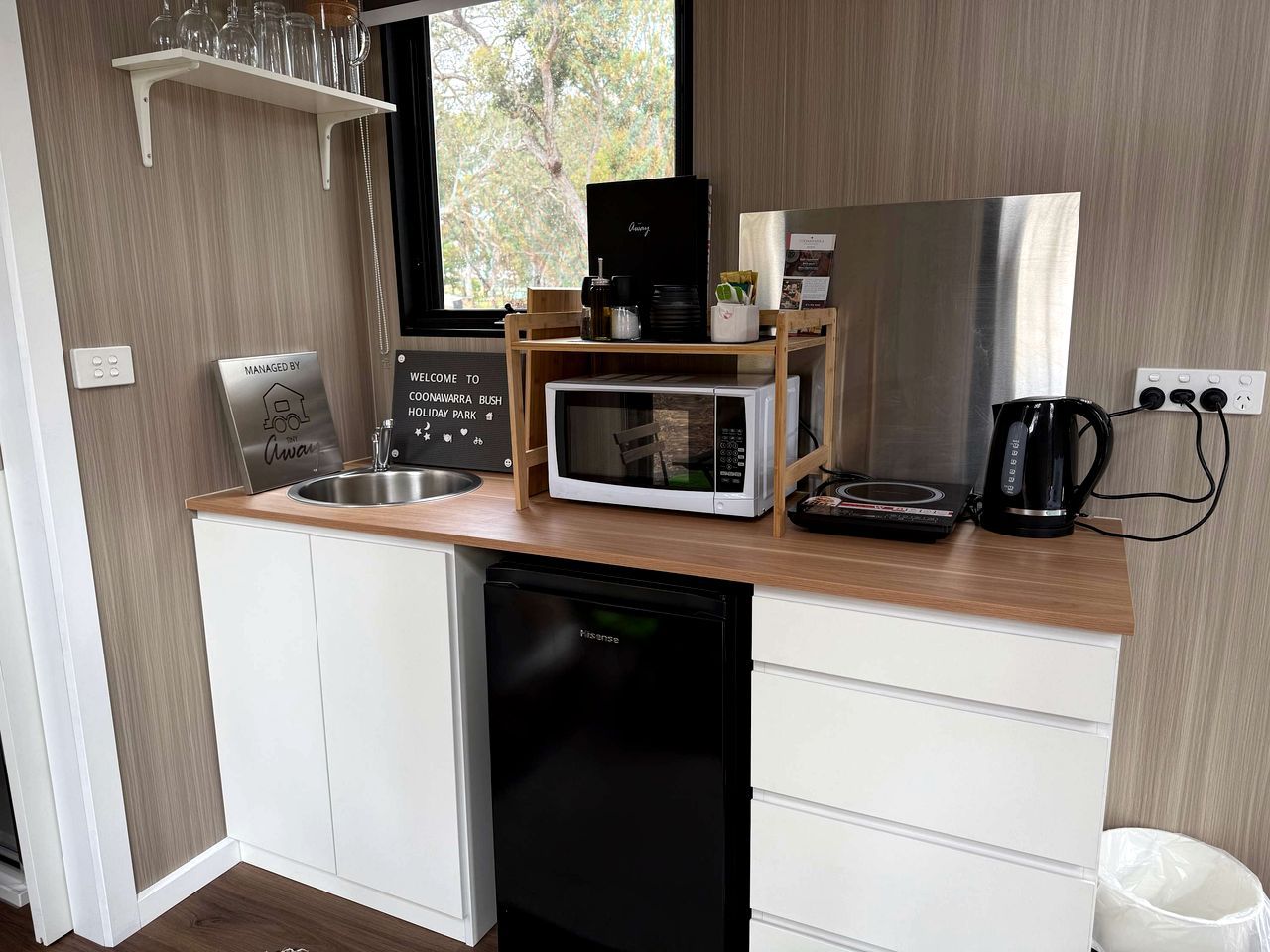 A compact kitchenette with a microwave, coffee maker, and a sink.