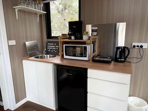 A compact kitchenette with a microwave, coffee maker, and a sink.