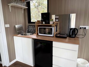 A compact kitchenette with a microwave, coffee maker, and a sink.