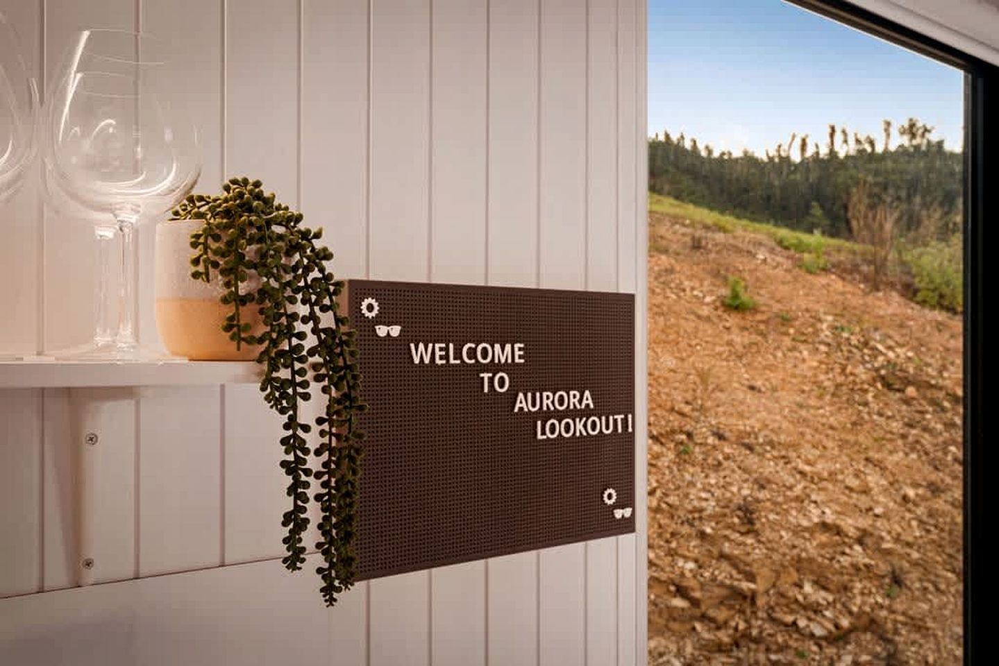 A welcome sign for Aurora Lookout with a view of a forested landscape.