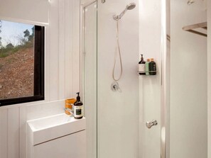 A bathroom with a shower, a sink, and a window.