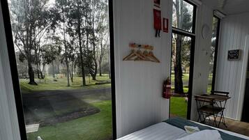 Ett sovrum med ett stort fönster, en säng, ett litet bord och en stol.