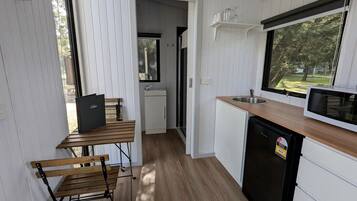Una cocina funcional con una mesa de madera, un refrigerador negro y un microondas en la encimera.