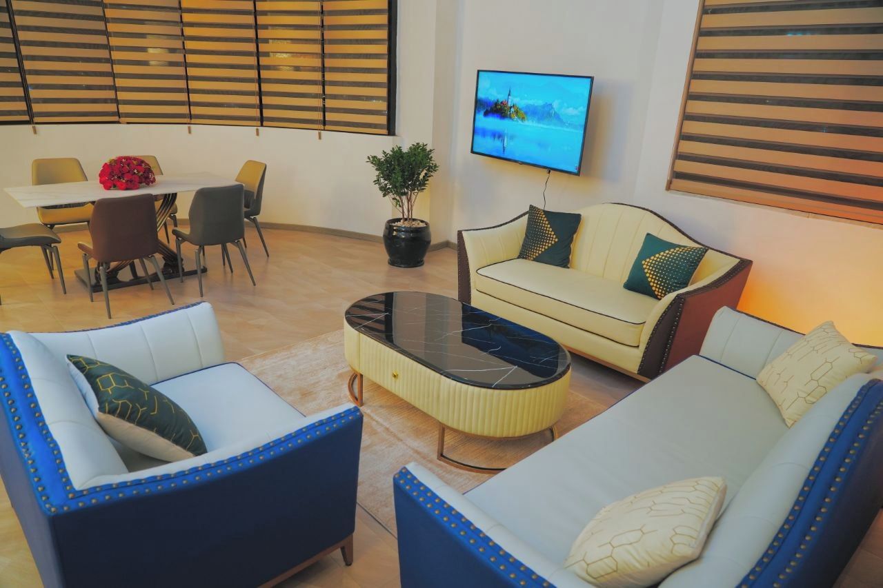 Una sala moderna con sofá, sillones, una mesa de centro y un comedor con sillas y una mesa.