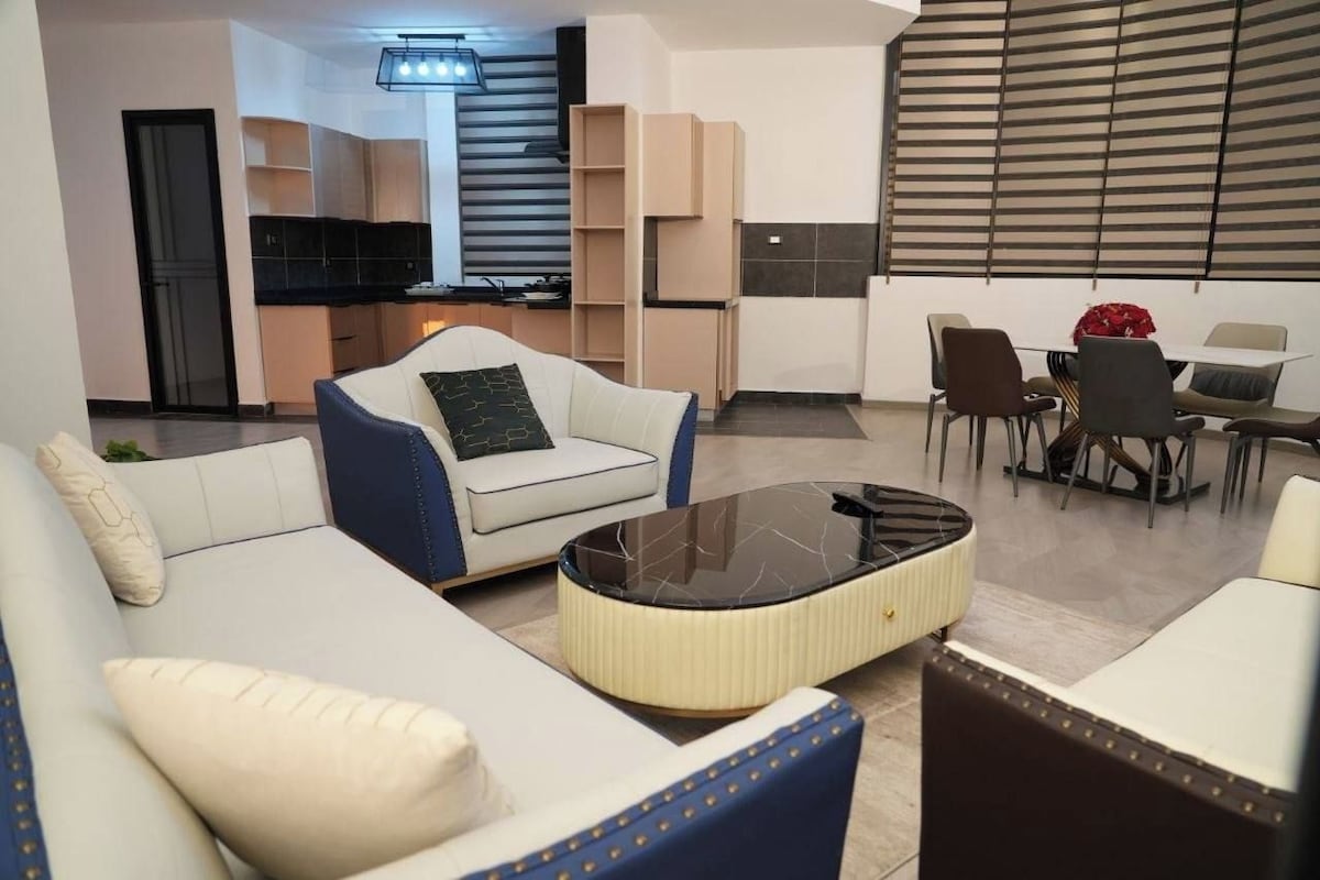 A modern living room with a sofa, a coffee table, and a dining area with chairs and a table.
