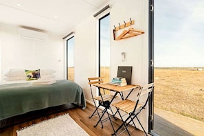 Un dormitorio con cama, escritorio y vistas al paisaje.