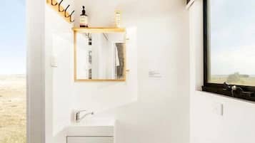 Een kleine, moderne badkamer met een wit wastafelmeubel, een toilet en een spiegel boven de wastafel.