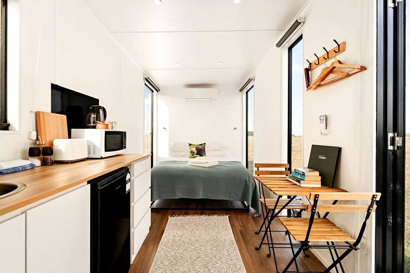 Une pièce compacte comprenant un coin cuisine, un lit, un bureau et une chaise.