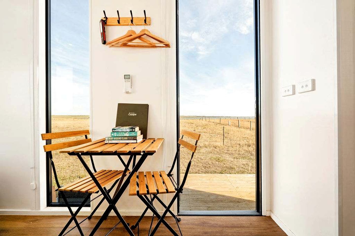 A room with a wooden table and chairs, a coat rack, and a bookshelf with books.