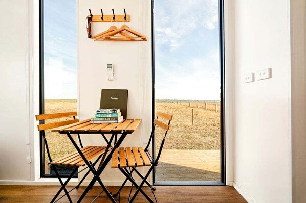 Une pièce avec une table et des chaises en bois, un porte-manteau et une bibliothèque remplie de livres.