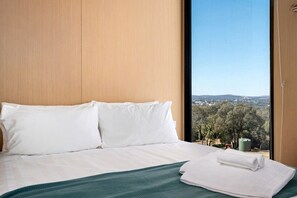 A hotel room with a bed, a view of the countryside, and a window.