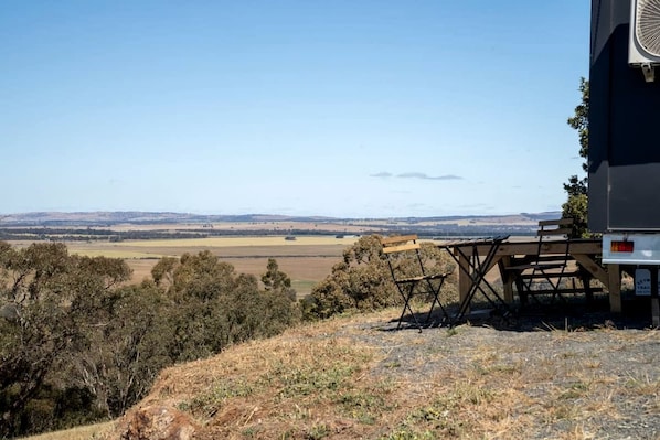 A scenic view with a table and chairs, a bench, and a building with a sign indicating a trail.