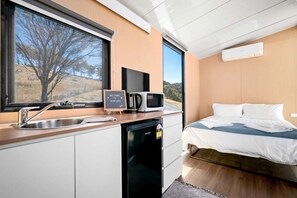 A compact room with a bed, a sink, a microwave, and a small refrigerator. - Marvelous Glamping Getaway for Two: Secluded and Tranquil Tiny House in Ararat, Victoria (Ararat)