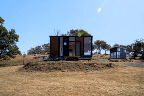 A modern, two-story cabin with a flat roof, large windows, and a small porch area.