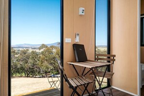 A room with a large window, a wooden table, and a bench. - Marvelous Glamping Getaway for Two: Secluded and Tranquil Tiny House in Ararat, Victoria (Ararat)