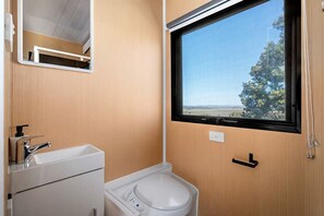 A compact bathroom with a toilet, sink, and window. - Marvelous Glamping Getaway for Two: Secluded and Tranquil Tiny House in Ararat, Victoria (Ararat)