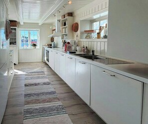Een keuken met witte kastjes, een lange aanrecht en een raam met uitzicht.