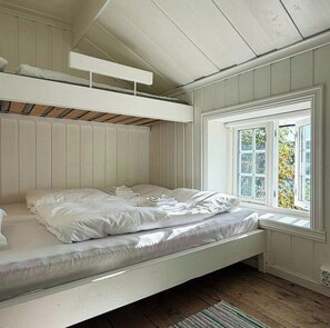 A bunk bed with a window, white walls, and a wooden floor. - **Historic Wooden House with Fjord Views (Råkvåg)