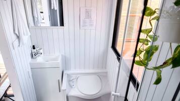 A compact bathroom with a toilet, sink, and towel rack.