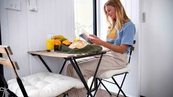 A person sitting at a small table with a book, a glass of orange juice, and a plate of fruit.