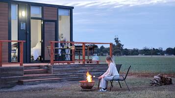 A modern building with a deck, outdoor seating, and a fire pit.