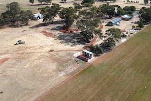 An aerial view of a rural property with a small building, open fields, and scattered trees.