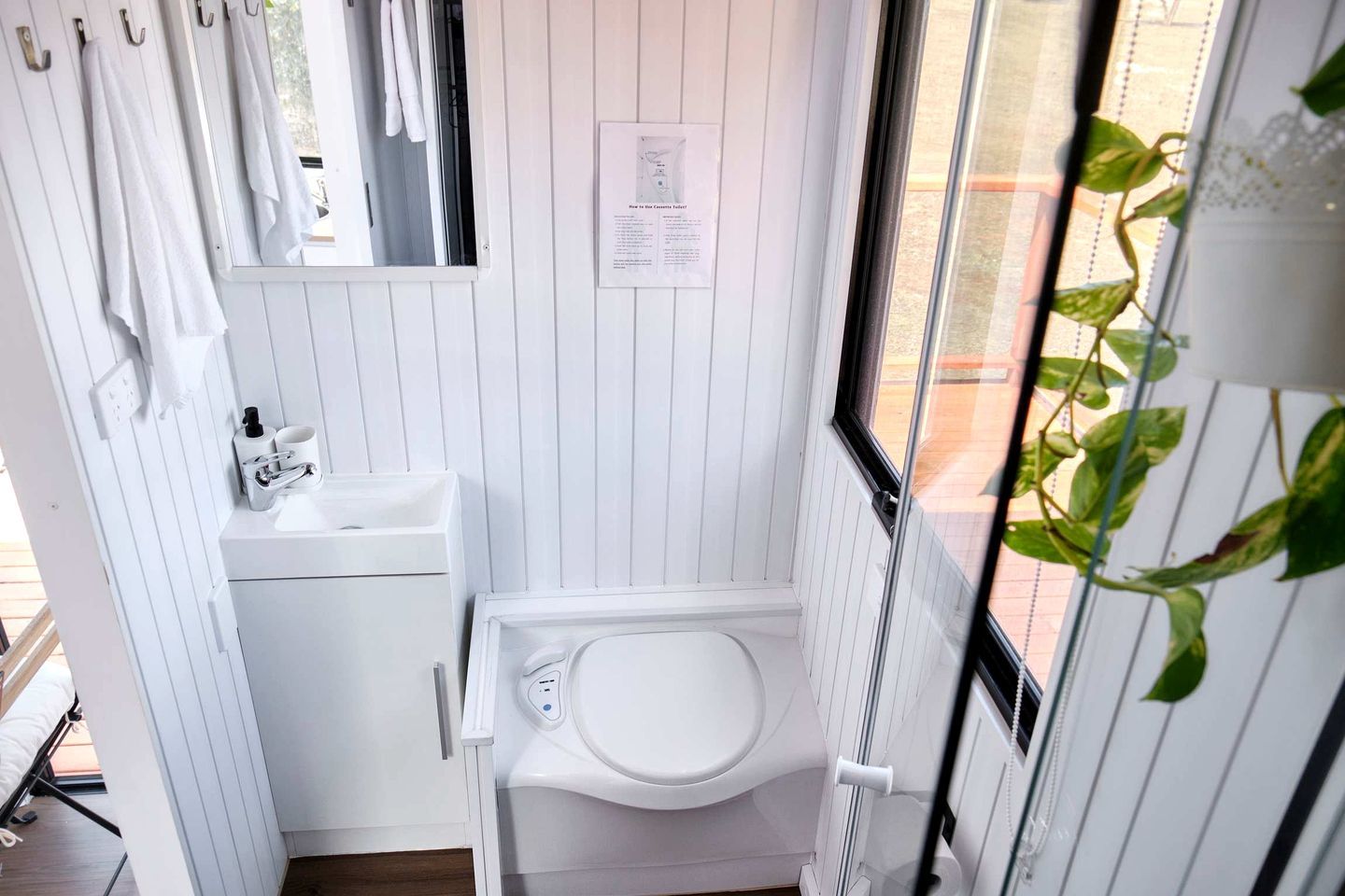 Et lille badeværelse med toilet, vask og håndklædestang.
