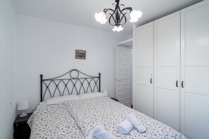 Ein Schlafzimmer mit einem Bett, einem Nachttisch, einem weißen Kleiderschrank und einer Deckenleuchte.