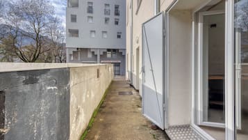 Un vialetto di cemento stretto conduce a un edificio con un'ampia porta in vetro e un cartello con su scritto 'mutuelle entrain'.