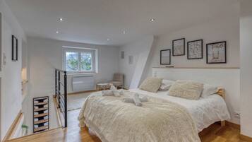 A bedroom with a bed, a chair, a window, and artwork on the wall.