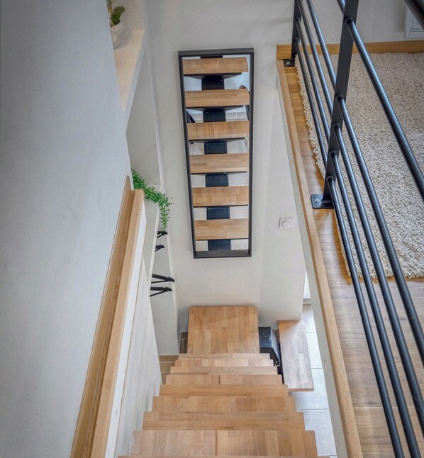 A wooden staircase with a black metal railing, leading to a landing with a black-framed window.